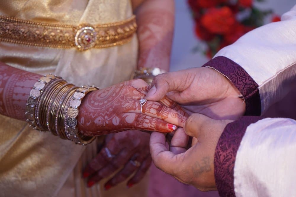 Pramod slipping the engagement ring onto Shravya's hennaed finger