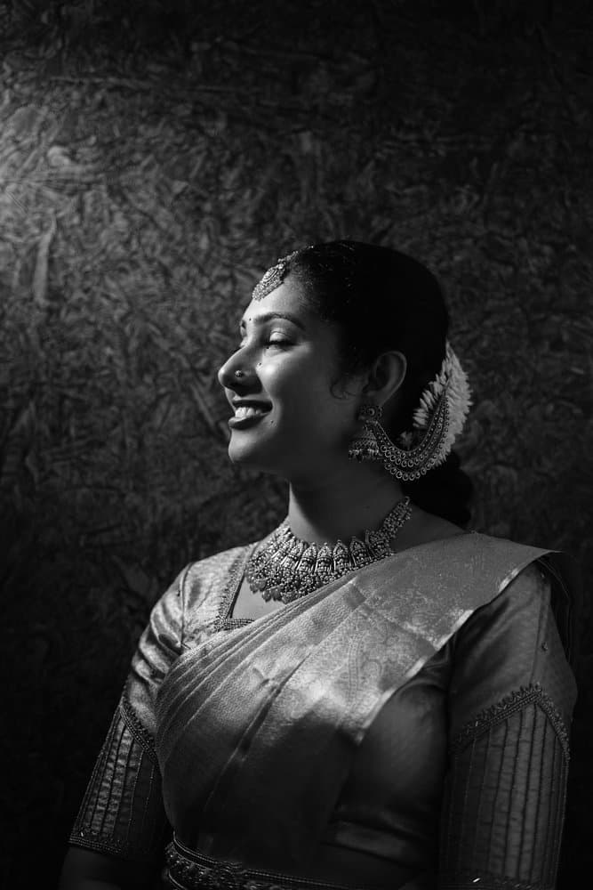 Black-and-white portrait of Shravya in profile, smiling, with jasmine in her hair